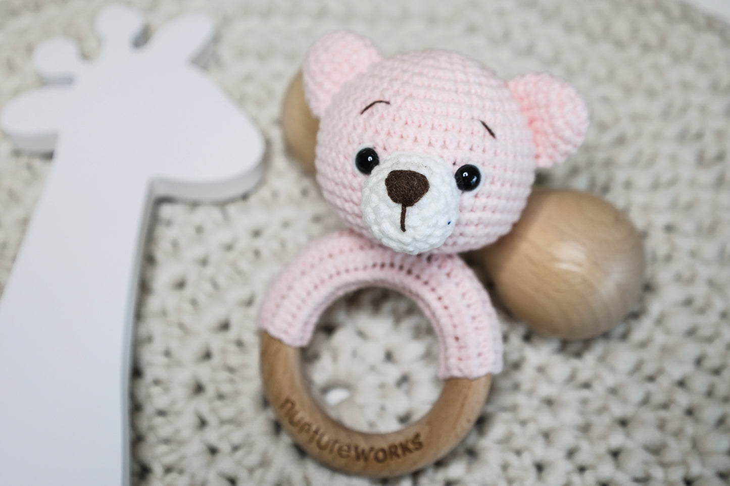 Pink crochet bear rattle with a wooden ring.