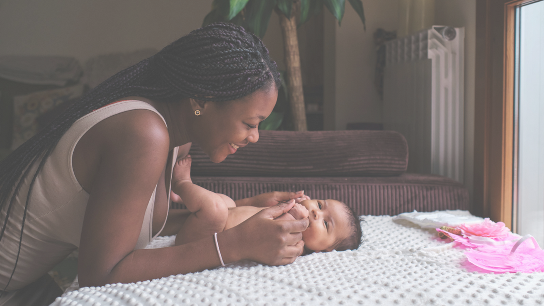 Mother holdinh newborn hands and smiling. 