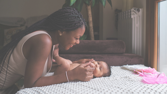 Mother holdinh newborn hands and smiling. 