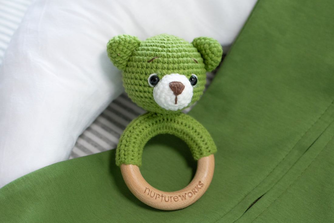 Green crochet rattle with wooden handle. 