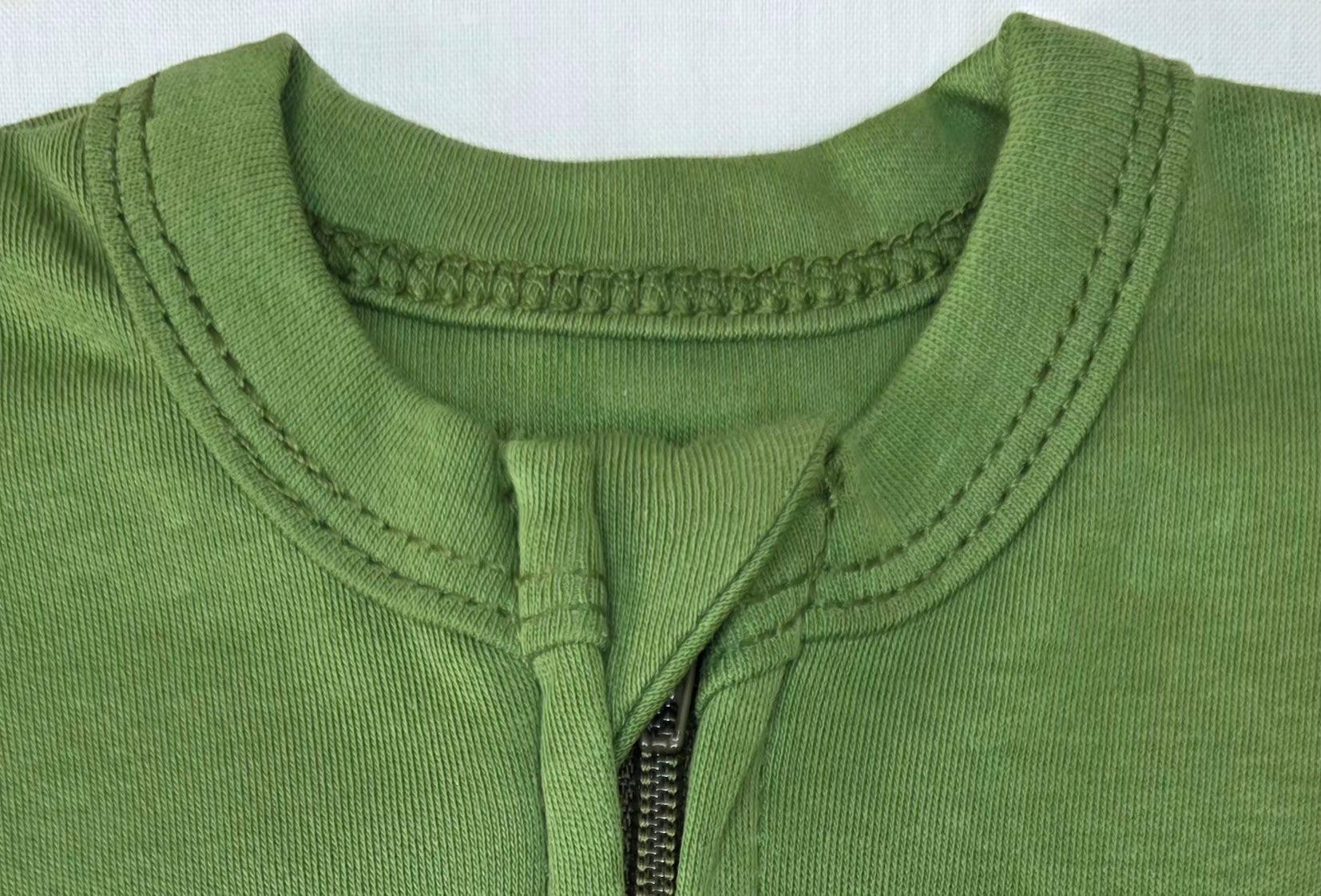 Close-up of a green sleep sack neckline with a zipper on a white background
