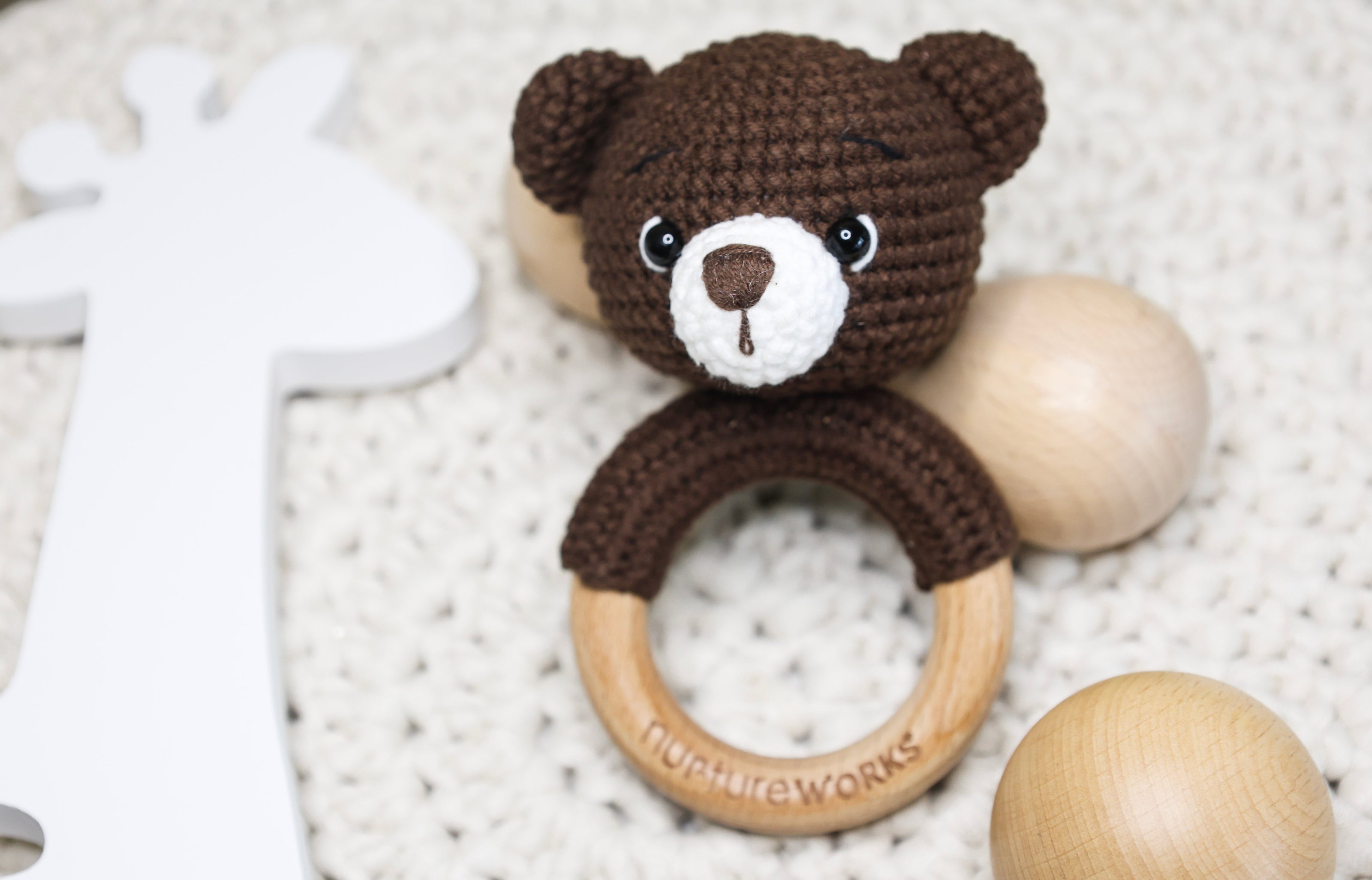 Brown crochet bear rattle with a wooden ring.
