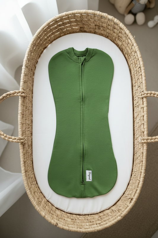 Green baby swaddle sleep sack in a wicker basket on a neutral background