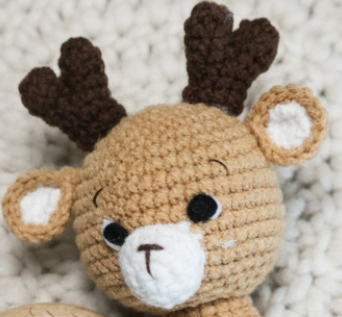Crocheted deer toy with brown antlers on a soft, neutral background