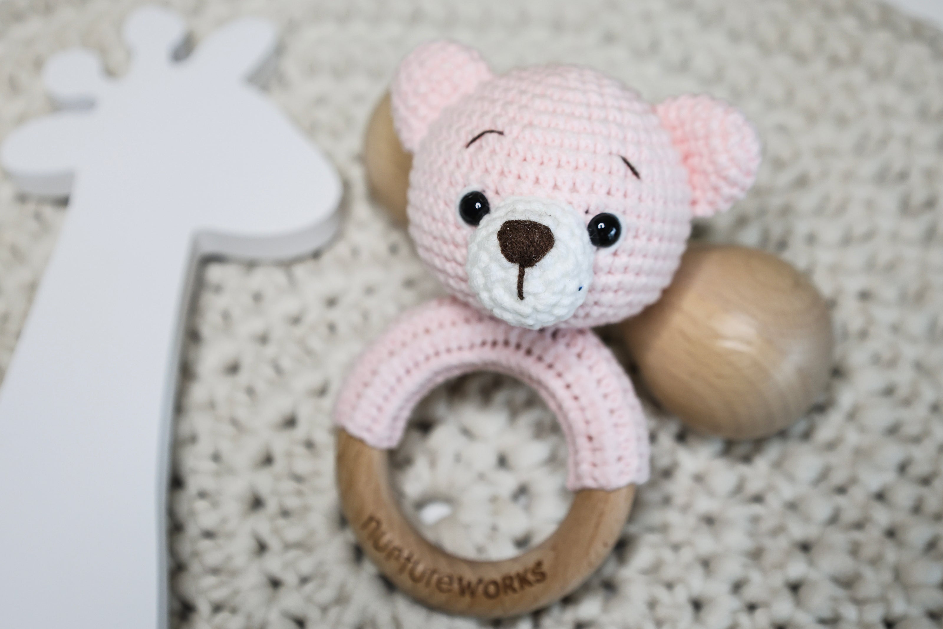 Pink crochet bear rattle with a wooden ring.