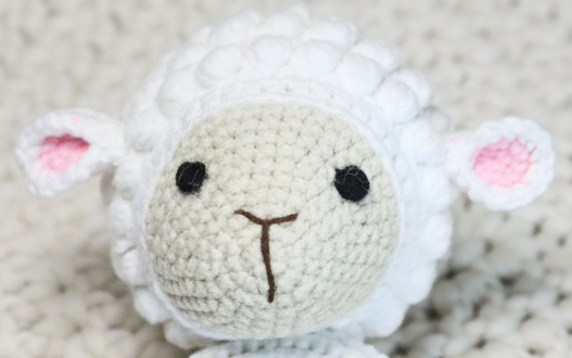 Crocheted sheep toy on a textured beige background